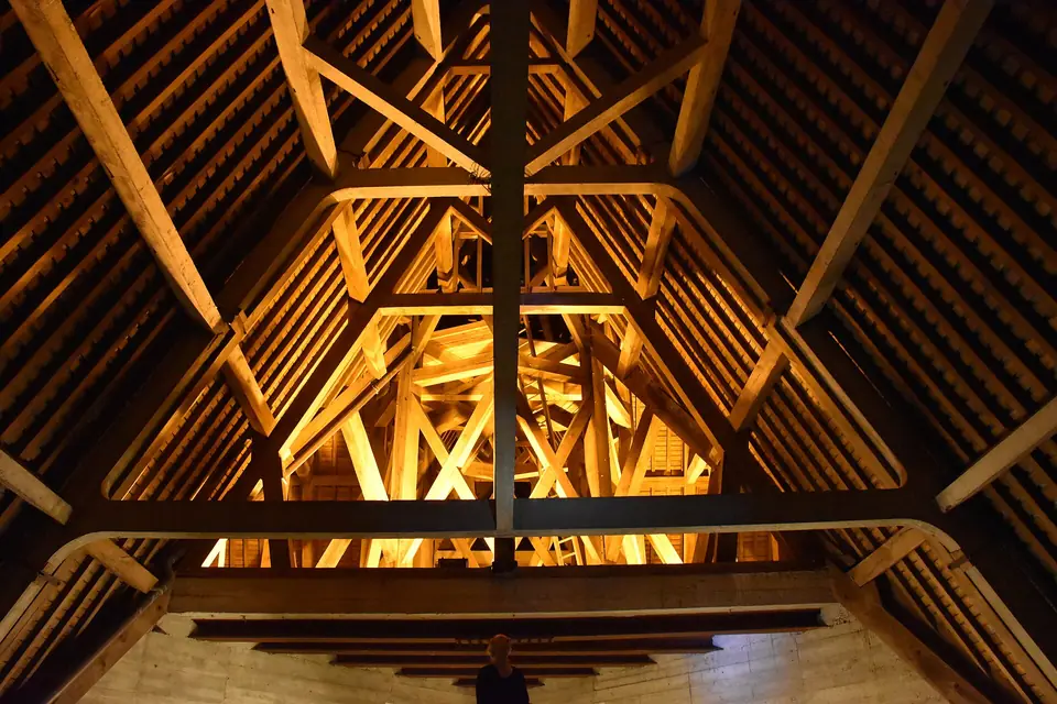 Intérieur de comble : grande charpente en bois avec fermes, entraits et chevrons.